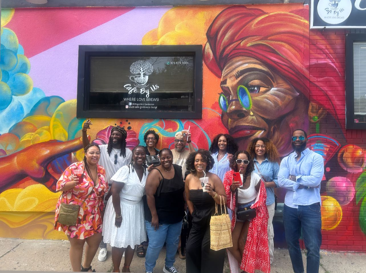 Guests posing in front of the Cafe By Us mural