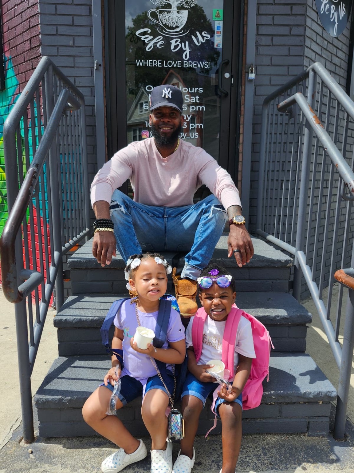 Samuel Breaker sitting on the cafe steps with two kids